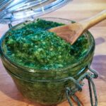 open jar of pesto with wooden spoon.