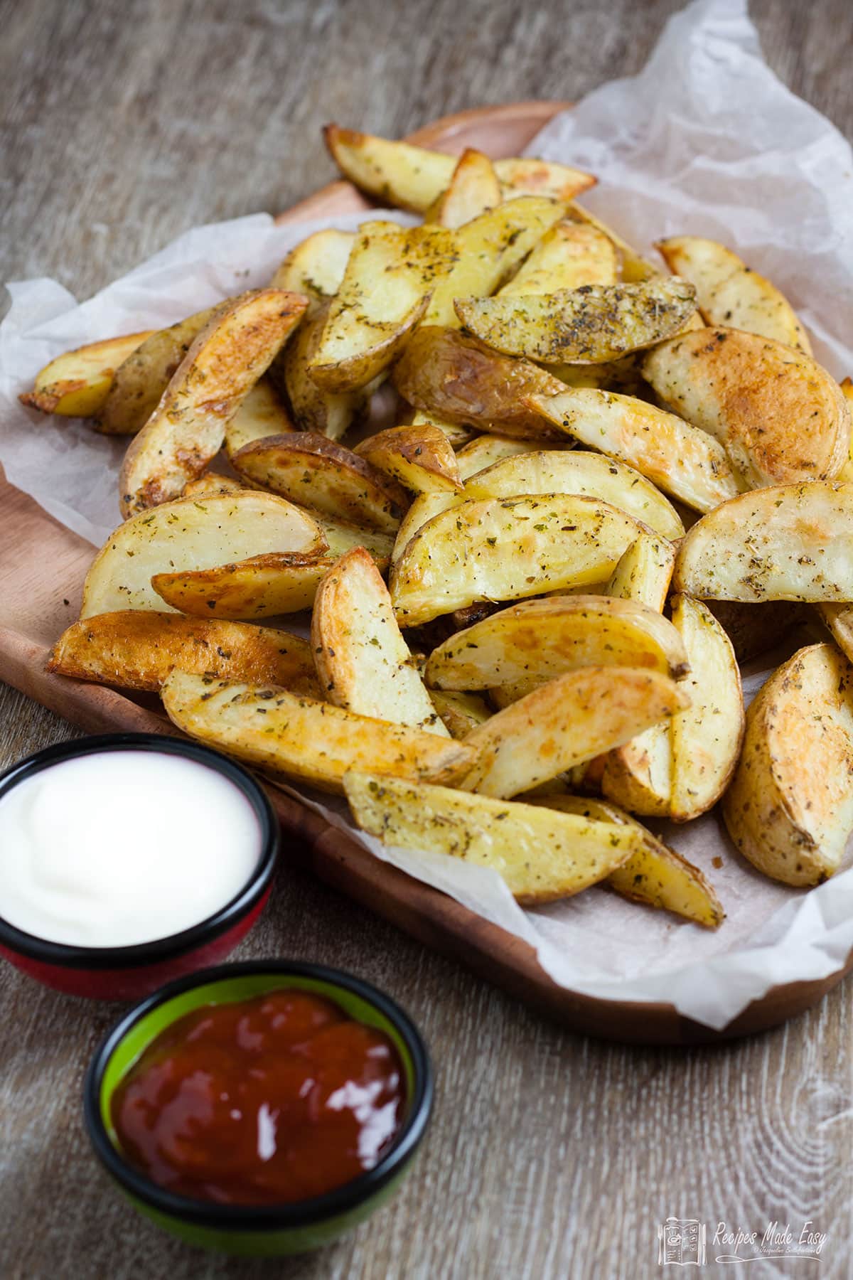 tray of oven chips with bowls of ketchup and mayo on the side.