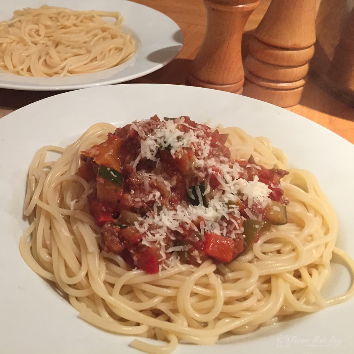 plate of spaghetti bolognese topped iwth parmesan.