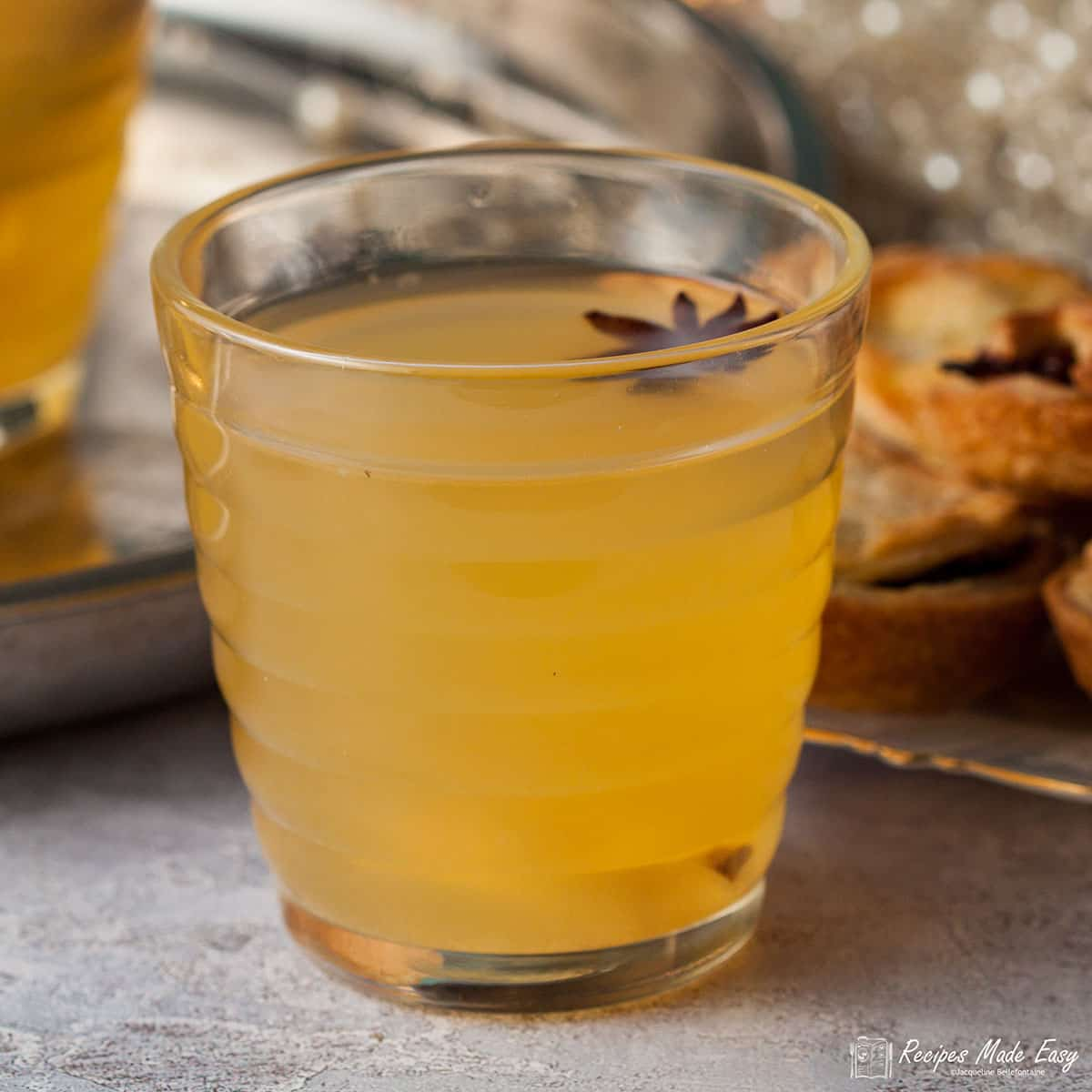 glass of mulled cider with a star anise flaoting on top.