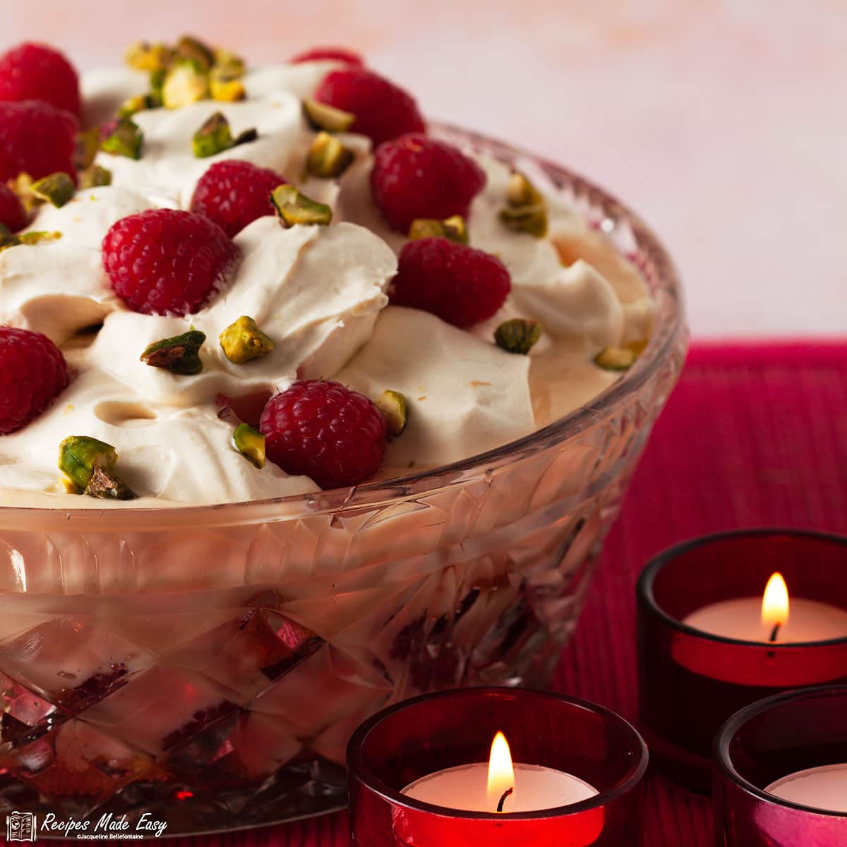 bowl of raspberry syllabub trifle with 3 candles in front.
