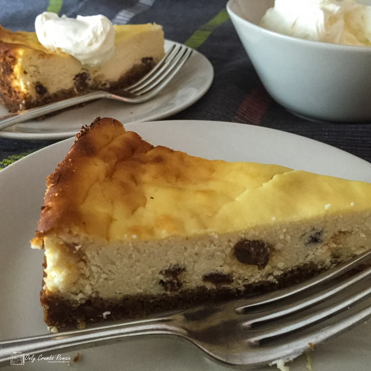 slice of baked lemon cheesecake on plate with second slice behind.