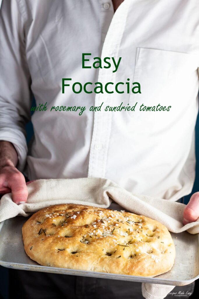man holding tray with focaccia loaf