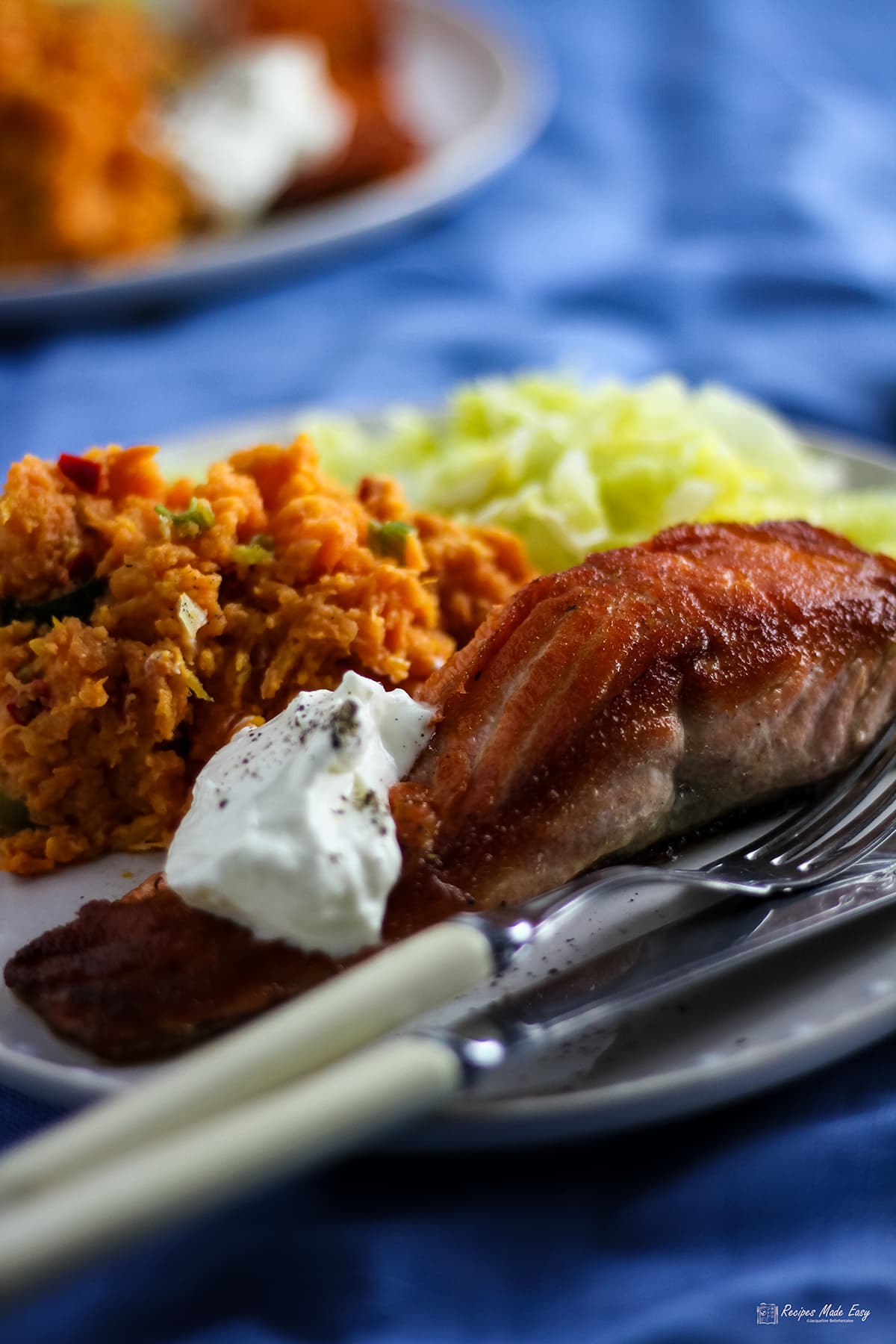 Pan-fried salmon and sweet potato chilli mash on a plate with fish knife and fork.