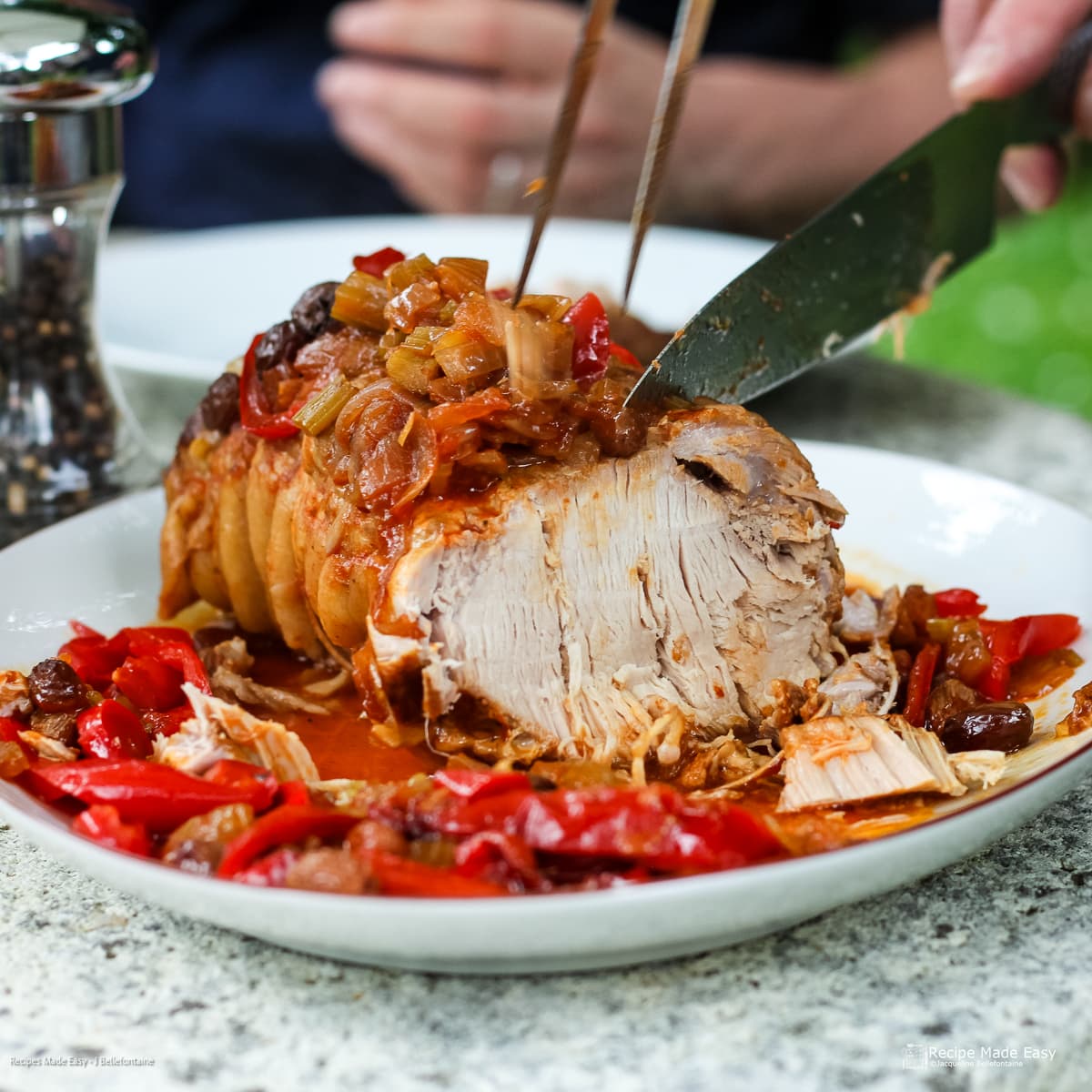Slow-cooed weet and sour pork on serving plater being carved into slices.