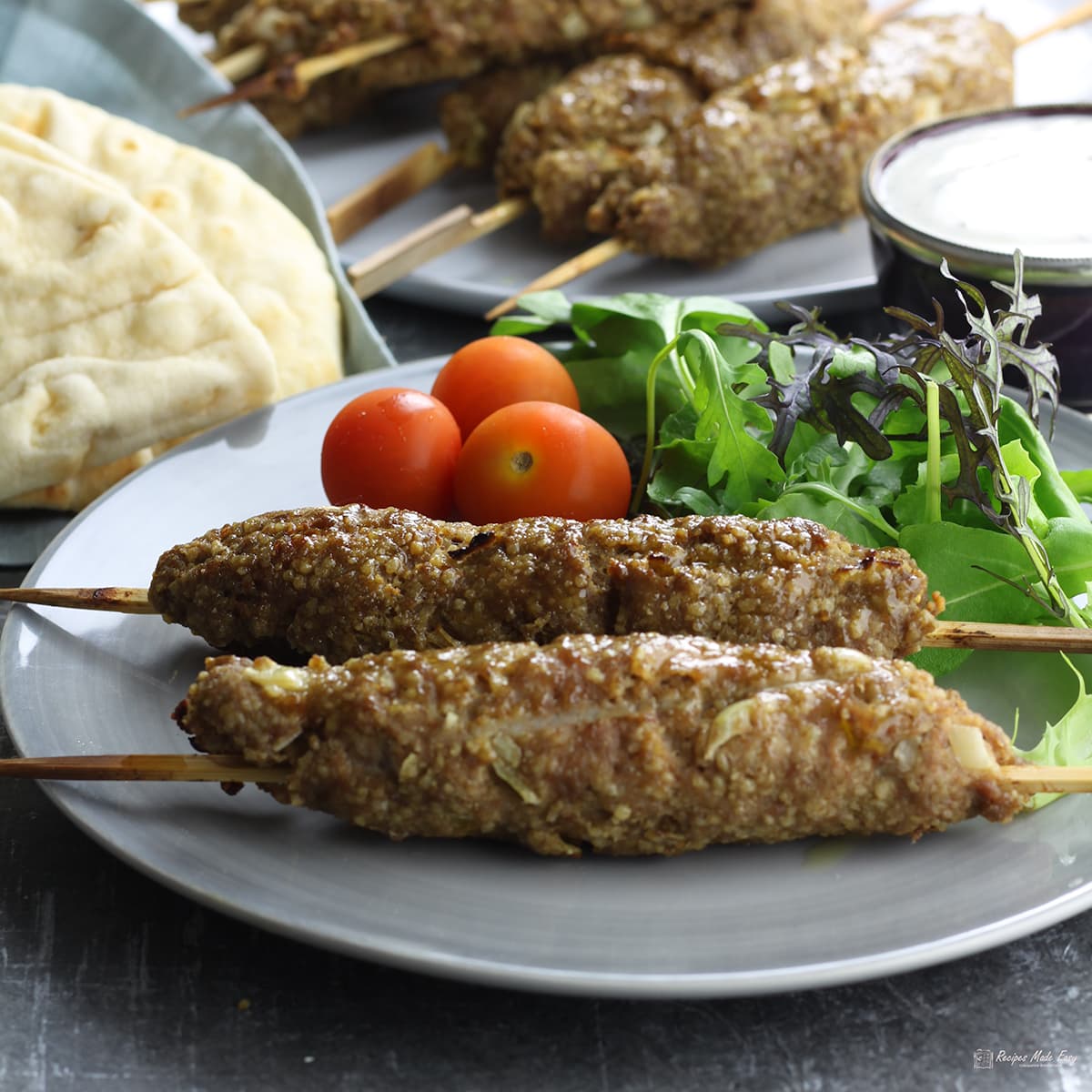 2 middle eastern style kebabs on plate with salad.