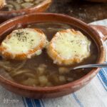 bowl of French onion soup with two cheese croutes on top.