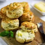 Halloumi and mint scones on a wooden board one split and spread with butter.