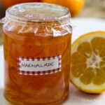 jar of marmalade next to half an orange.