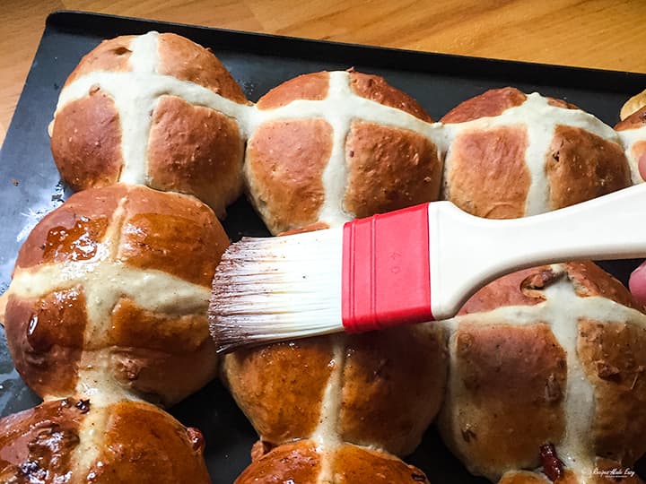 brushing glaze on hot cross buns.