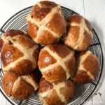 pecan cinnamon and ornge hot cross buns on a wire rack.a