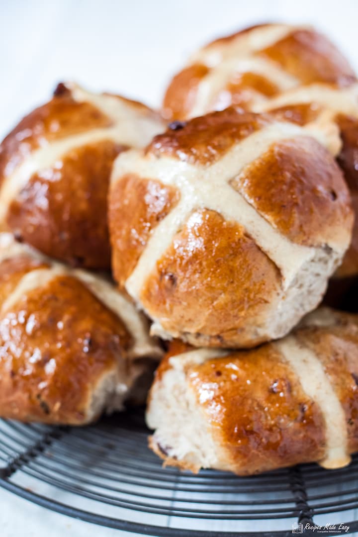 pecan, cinnamon and orange hot cross buns piled on a round wire rack.