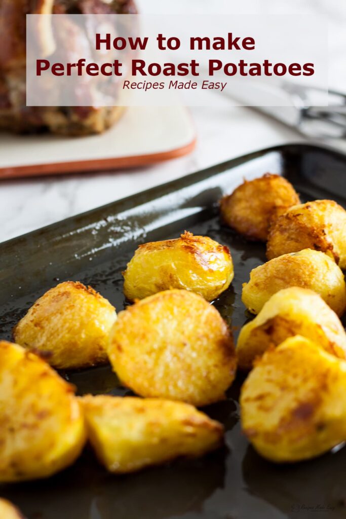 Roast potatoes on a baking tray in front of a joint of meat.