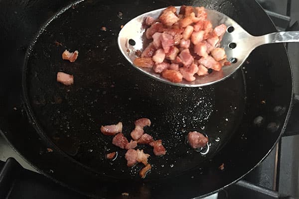 Removing pancetta from the pan.
