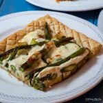 corner piece or courgette and asparagus tart on a plate.