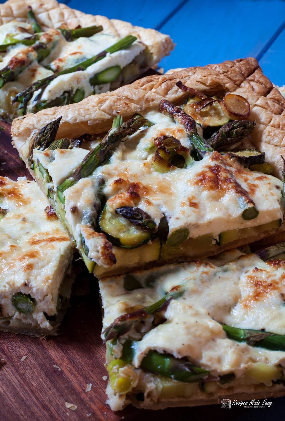 pieces of courgette and asparagus tart on a board.
