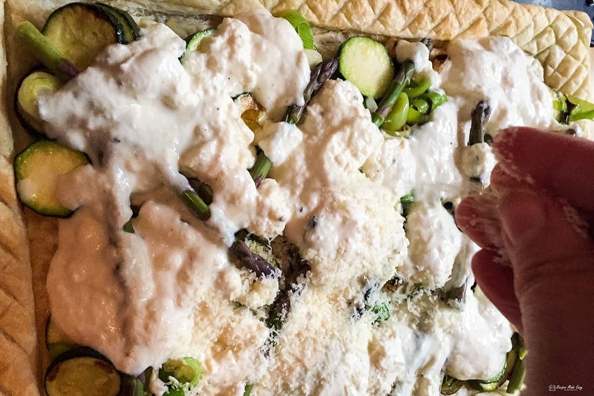 sprinkling parmesan on top of the uncooked tart.