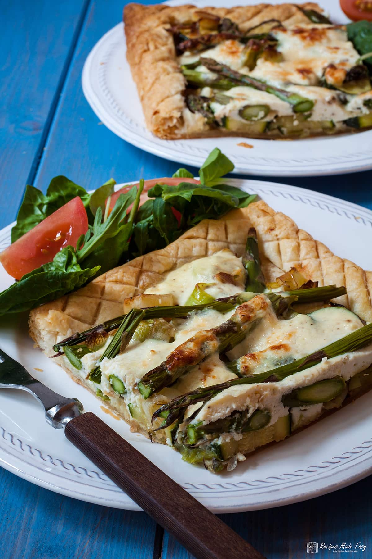 piece of courgette and leek tart on a plate with some side salad.