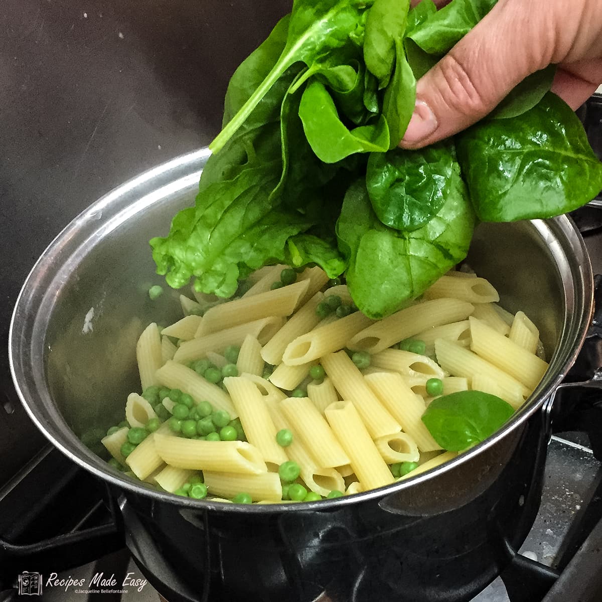 adding spinach to drained pasta and peas