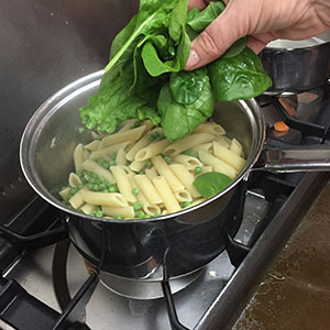 Drain and add the spinach. adding spinach to pan for penne with peas and spinach by recipesmadeeasy.co.uk