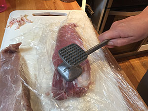 Pork being flattened with meat mallet
