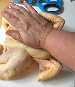 Press down firmly on the breast bone to flatten the chicken. Press down firmly on the breast bone to flatten the chicken.