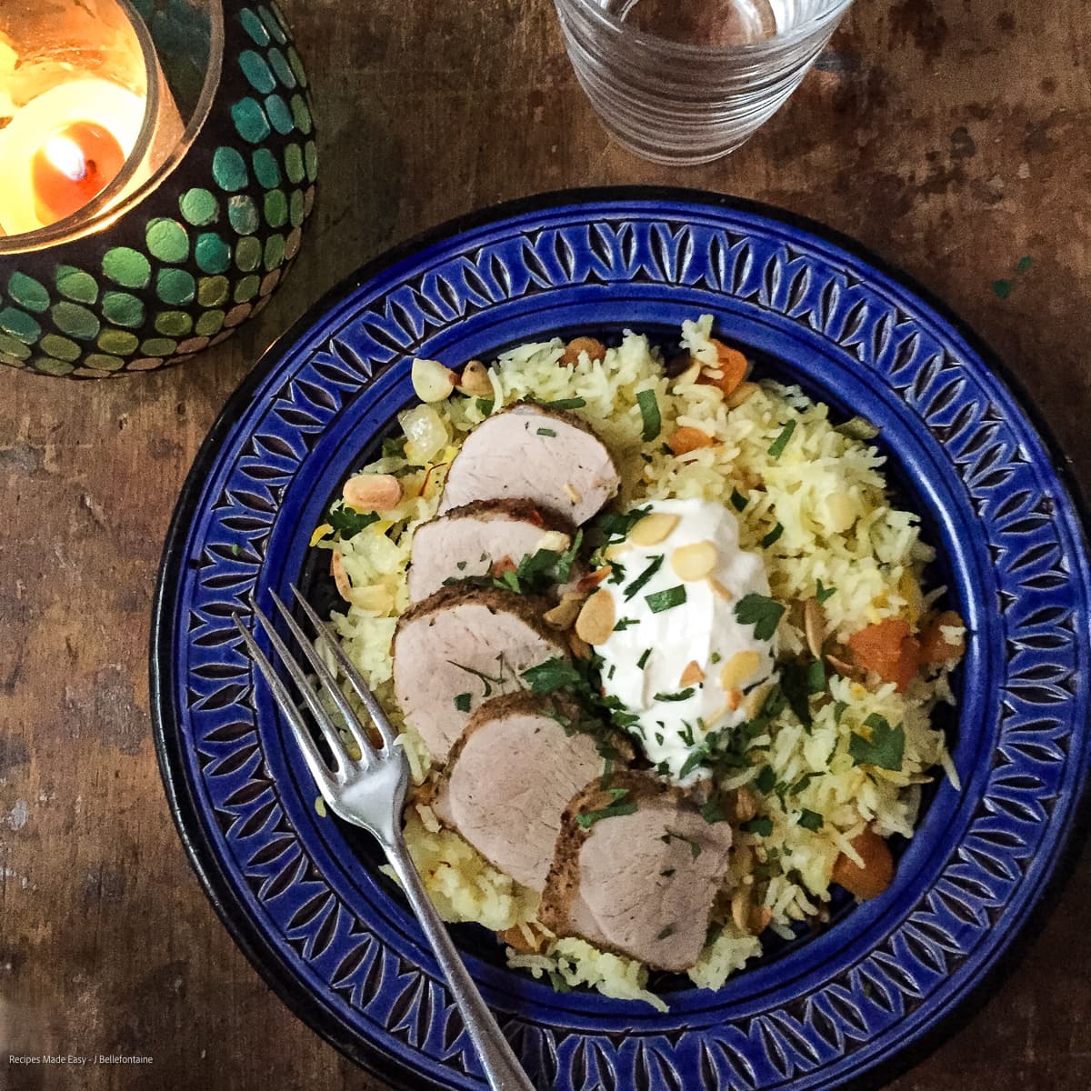 spiced pork with saffron and apricot rice garnished with yogurt and chopped parsley.