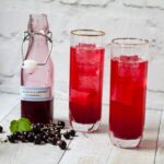open bottle of blackcurrant cordial with 2 glasses