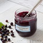 jar of blackcurrant jam with blackcurrants on the work surface