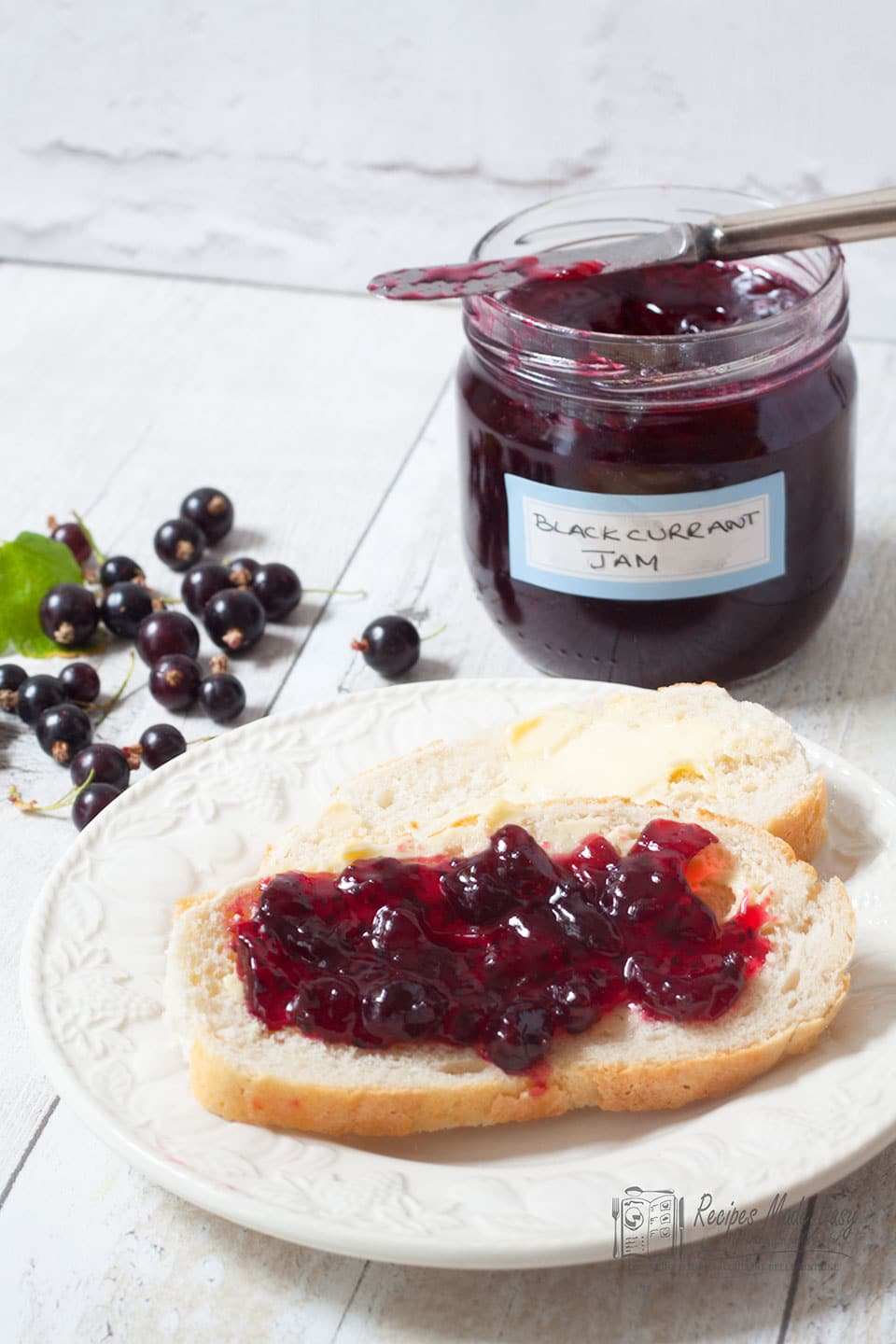 blackcurrant jam spread on bread with jar in background
