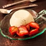 green glass dish of Basil Panna Cotta with Balsamic Strawberries.