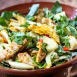 saffron chicken and herb salad in brown bowl.