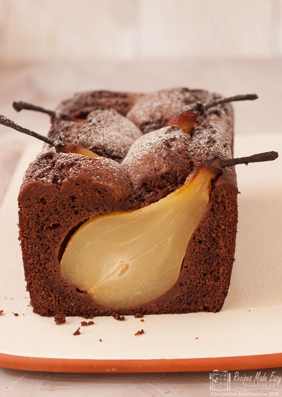 Sunken pear and chocolate cake by Recipes Made Easy, shown with a slice cut from the end