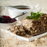 chestnut and sausagemeat stuffing cooked in tin with cranberry sauce and gravy jug behind.