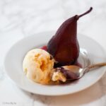 poached pear served with icecream. Spoon in dish.