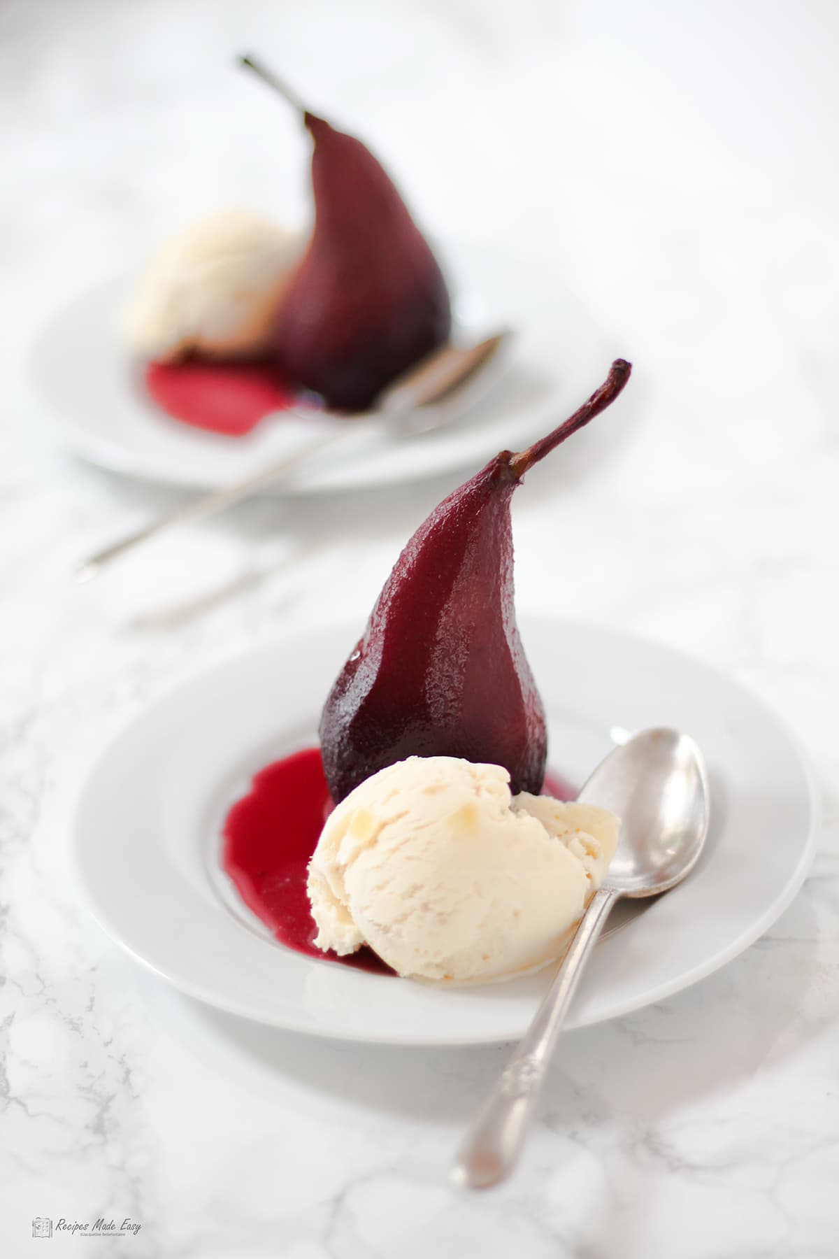 2 plates of pears in red wine served with stem ginger ice cream