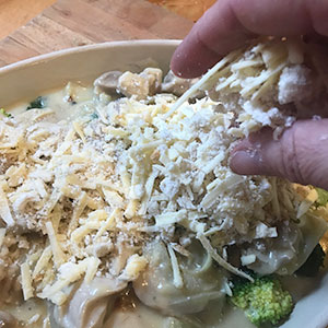 sprinkling cheese and crumbs onto dish.