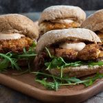 4 fried chicken sandwiches on a wooden board