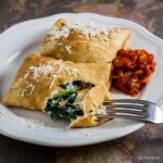 two spinach and ricotta pancakes with easy tomato sauce on the side.