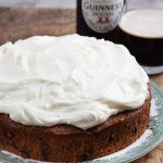 whole guinness cake on a plate with bottle and glass behind