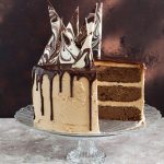 Mocha drip cake on cake stand with sliced removed