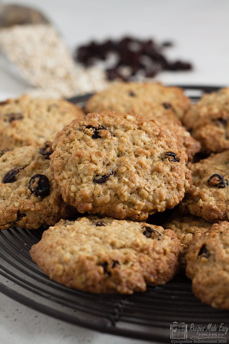oat and raisin cookies on a wire plate with oats and raisins in the distance
