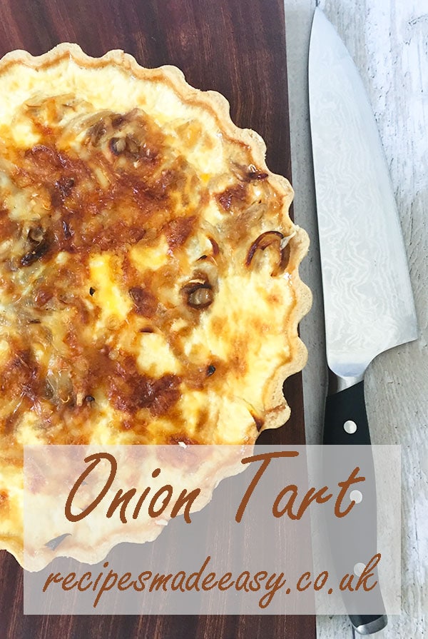 onion tart on board with knife by the side of board