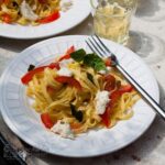 plate of tagliatelle with fresh tomatoes, basil and mozzarella with fork on the side.