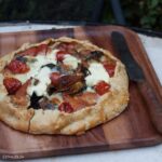 open summer vegetable pie on wooden board with old knife.