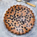 Blackberry, almond and rosemary tart on a glass serving plate.