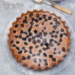 overhead shot of blackberry, almond and rosemary tart on a glass plate