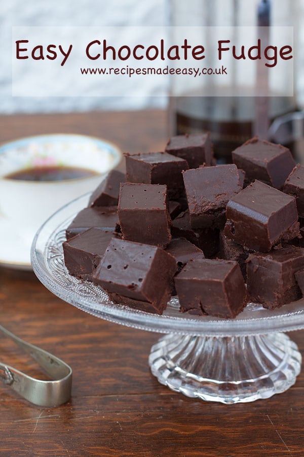 chocolate fudge on a cake stand with coffee cup in background