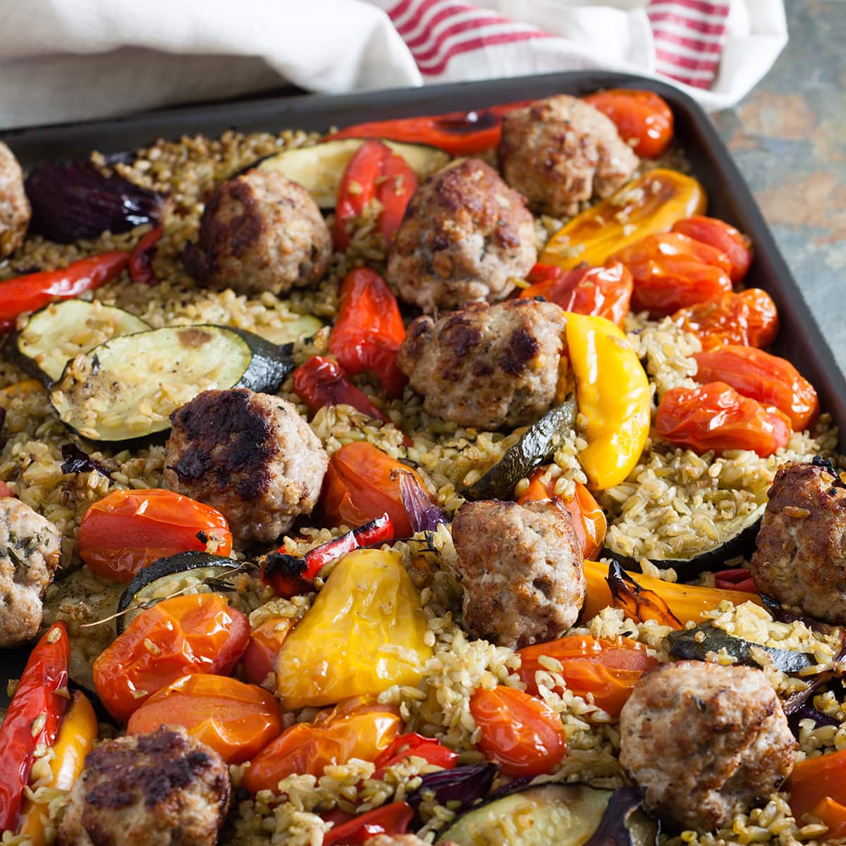 pork, lemon and thyme meatballs with roasted veg and freekeh on a baking tray