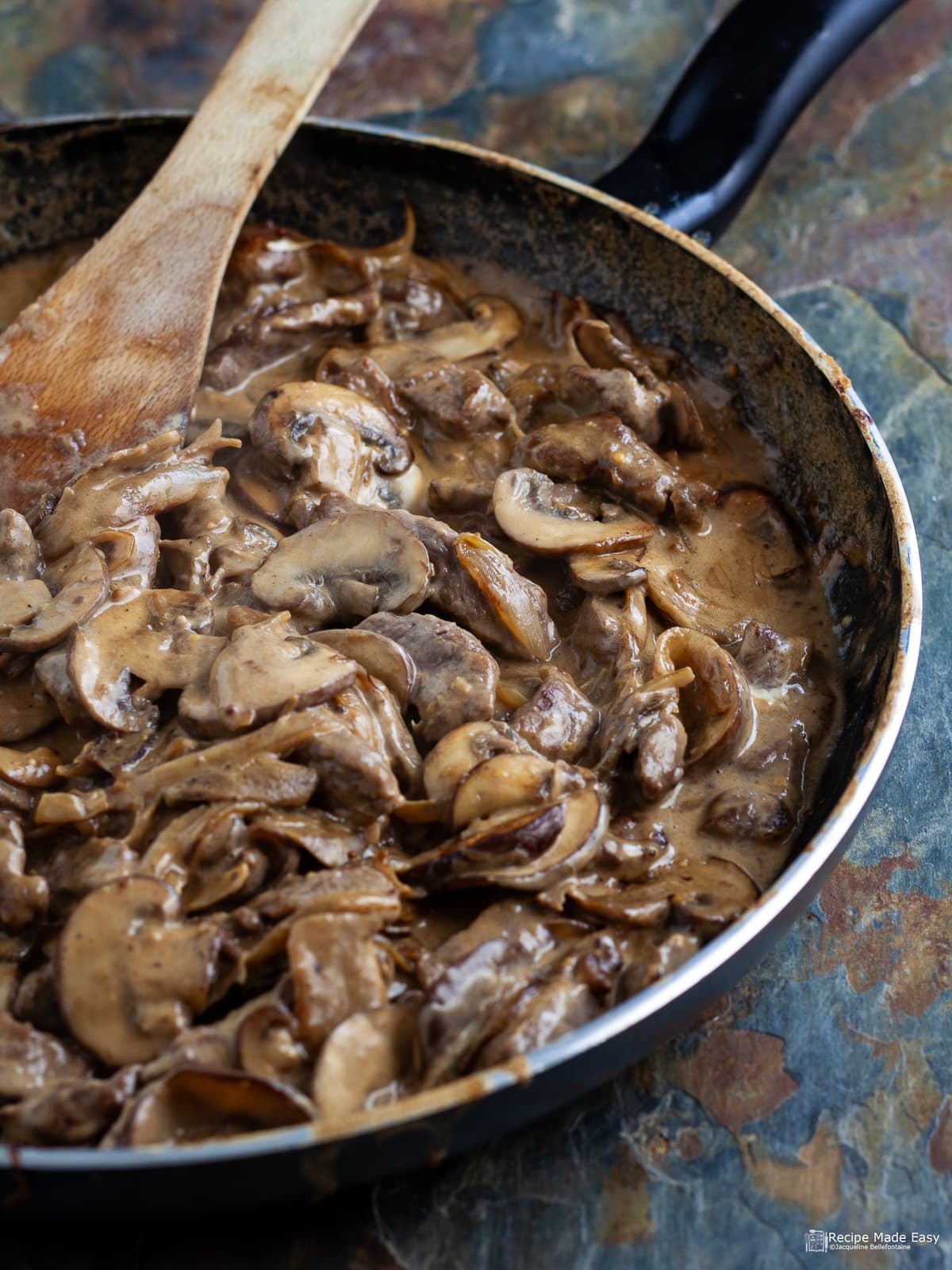 East beef stroganoff in a pan with a wooden spatula
